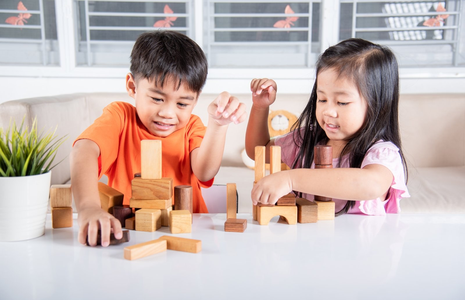 Two children building a tower with wooden blocks