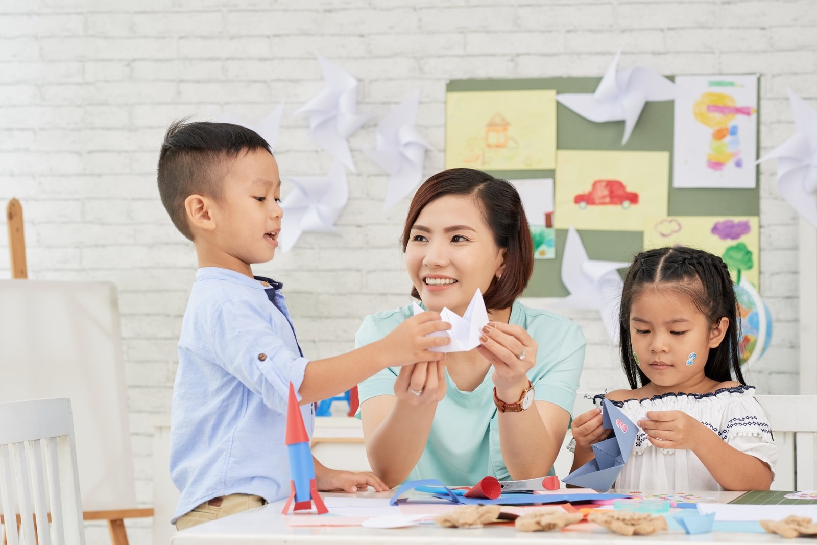 A teacher folding paper with two children
